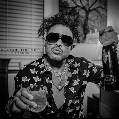 man watching a band on the stage wearing a red t-shirt and black hat.